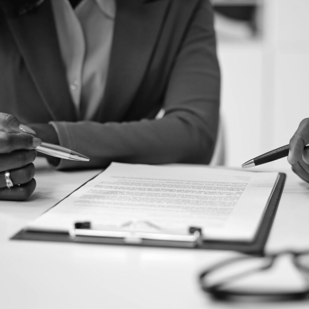 Two people reviewing a legal contract and pointing to sections on a clipboard.